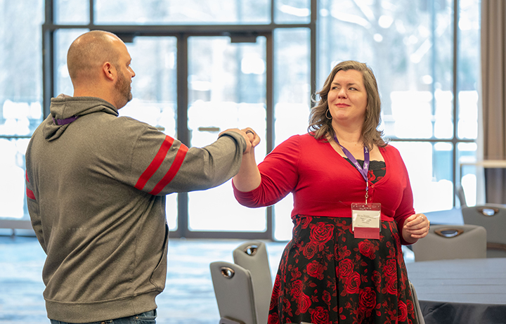 Two educators bumping fists at a conference